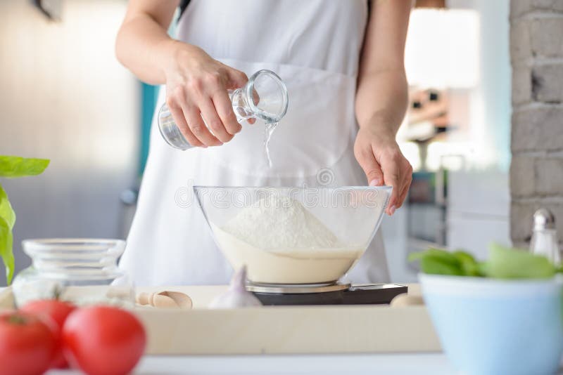 Vrouw die water toevoegt aan bloem in een kom stock afbeelding Vrouw die water toevoegt aan bloem in een kom stock afbeelding