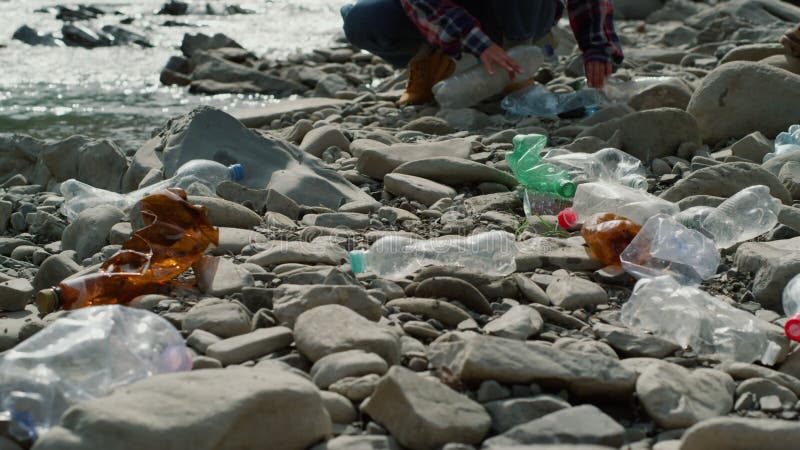 Vrouw en man die op de vuile kust van de rivier lopen. vrijwilligers die afval verzamelen