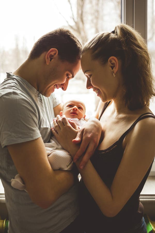 Vrouw en man holding op handen pasgeboren Op het achtergrondvenster Mamma, Papa en Baby Portret van jonge familie Gelukkig gezins stock foto Vrouw en man holding op handen pasgeboren Op het achtergrondvenster Mamma, Papa en Baby Portret van jonge familie Gelukkig gezins stock foto