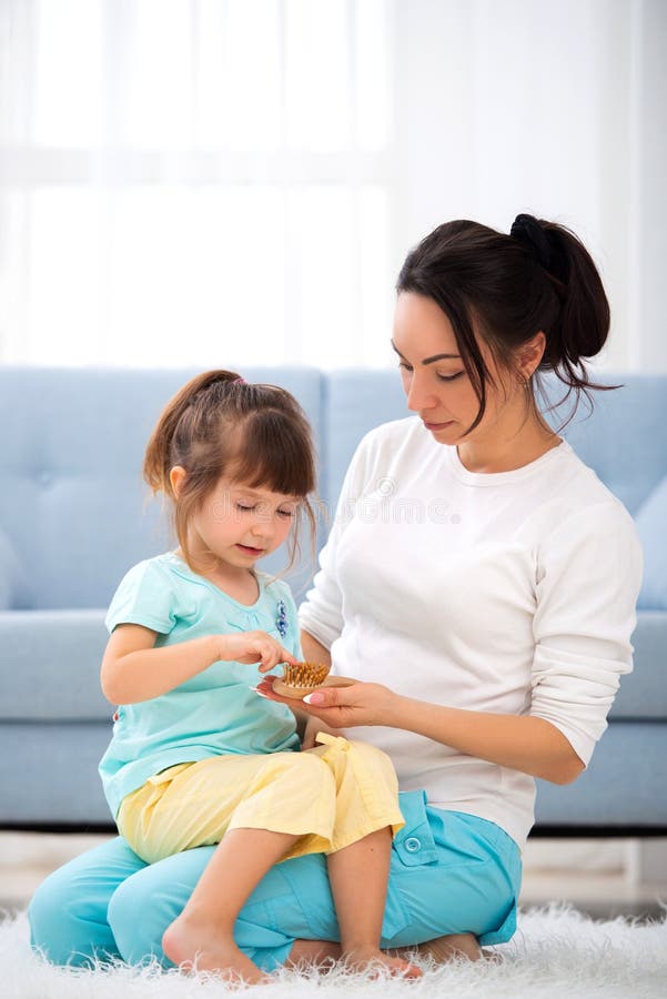 Woman and little girl sitting on carpet on the floor at home. Young mother talking communicates with small daughter. Best friends, happy motherhood. Woman and little girl sitting on carpet on the floor at home. Young mother talking communicates with small daughter. Best friends, happy motherhood