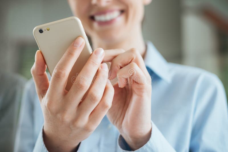 Vrouw gebruikend een smartphone en leunend op een venster stock fotografie Vrouw gebruikend een smartphone en leunend op een venster stock fotografie