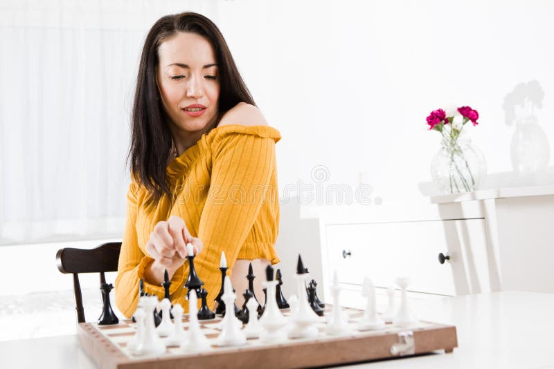 Vrouw in gele kledingszitting voor schaak - koninginbeweging stock fotografie Vrouw in gele kledingszitting voor schaak - koninginbeweging stock fotografie
