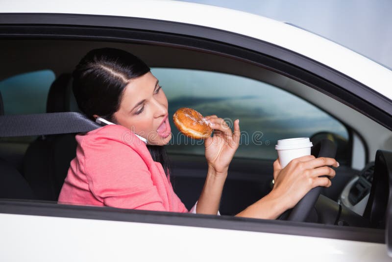 Woman drinking coffee and eating donnut on phone in her car. Woman drinking coffee and eating donnut on phone in her car