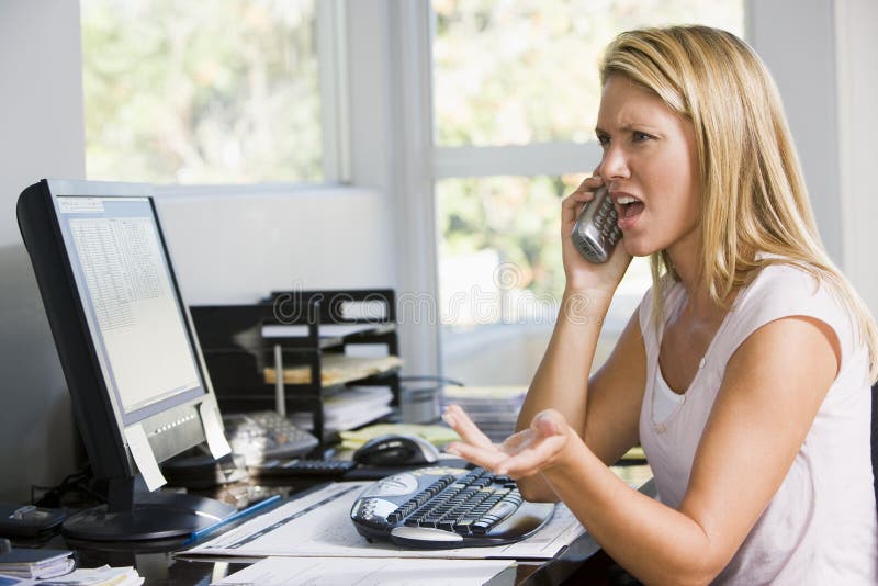Vrouw in huisbureau met computer die telefoon met behulp van royalty-vrije stock fotografie Vrouw in huisbureau met computer die telefoon met behulp van royalty-vrije stock fotografie