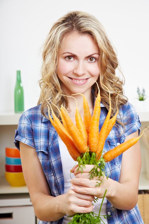 Smiling happy woman in her kitchen with bunch of carrots. Smiling happy woman in her kitchen with bunch of carrots