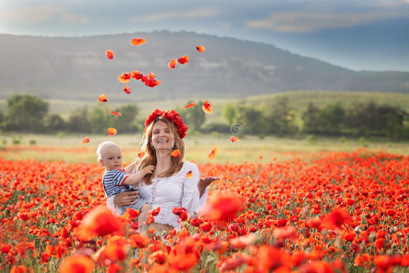 Vrouw met baby op een gebied van rode papavers stock fotografie Vrouw met baby op een gebied van rode papavers stock fotografie