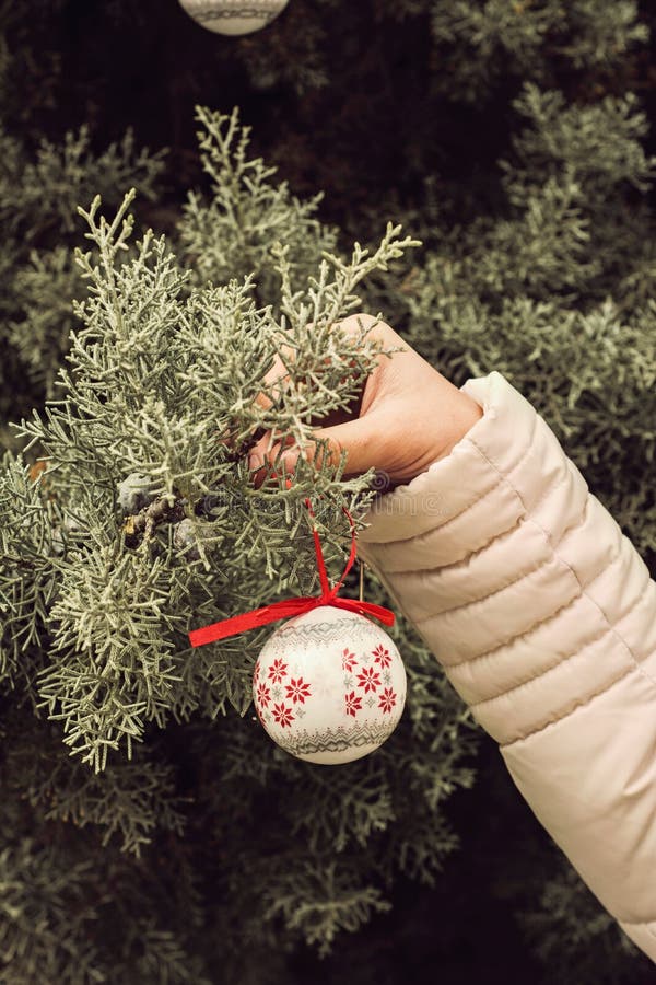 Vrouw, met een bal die Kerstboom, in handen verfraait openlucht stock foto Vrouw, met een bal die Kerstboom, in handen verfraait openlucht stock foto