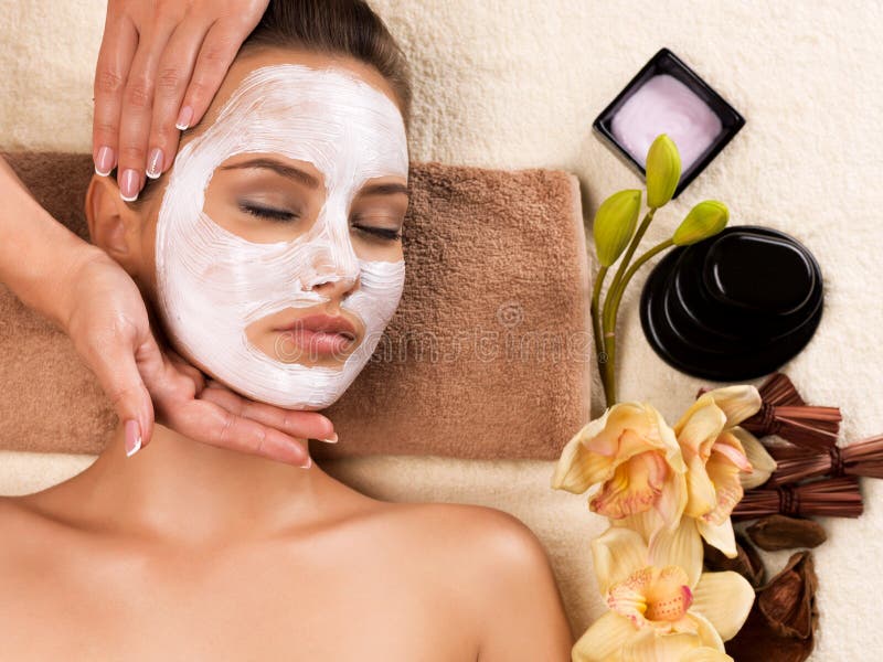 Vrouw met een masker op haar gezicht met een hoofdmassage stock afbeelding Vrouw met een masker op haar gezicht met een hoofdmassage stock afbeelding
