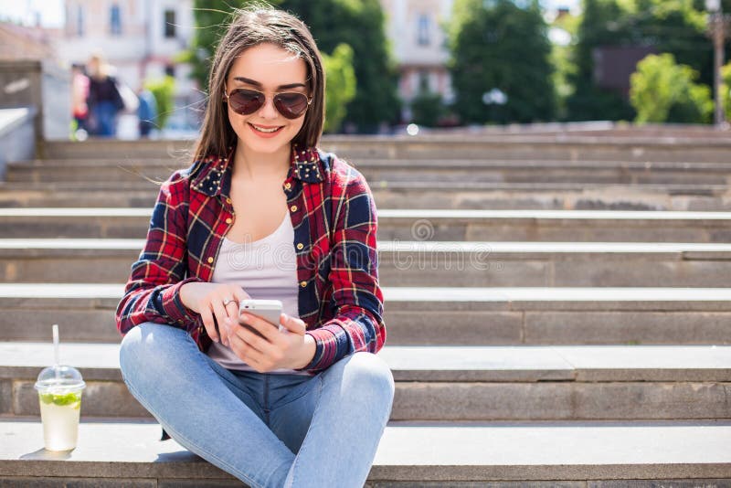 Vrouw met een verse kopzitting op de treden en het gebruiken van haar smartphone voor mededeling royalty-vrije stock afbeelding Vrouw met een verse kopzitting op de treden en het gebruiken van haar smartphone voor mededeling royalty-vrije stock afbeelding