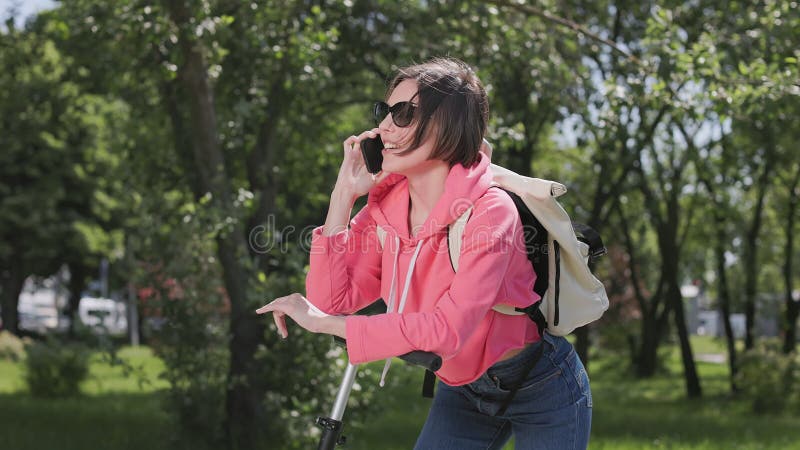 Vrouw met escoter die met smartphone spreekt
