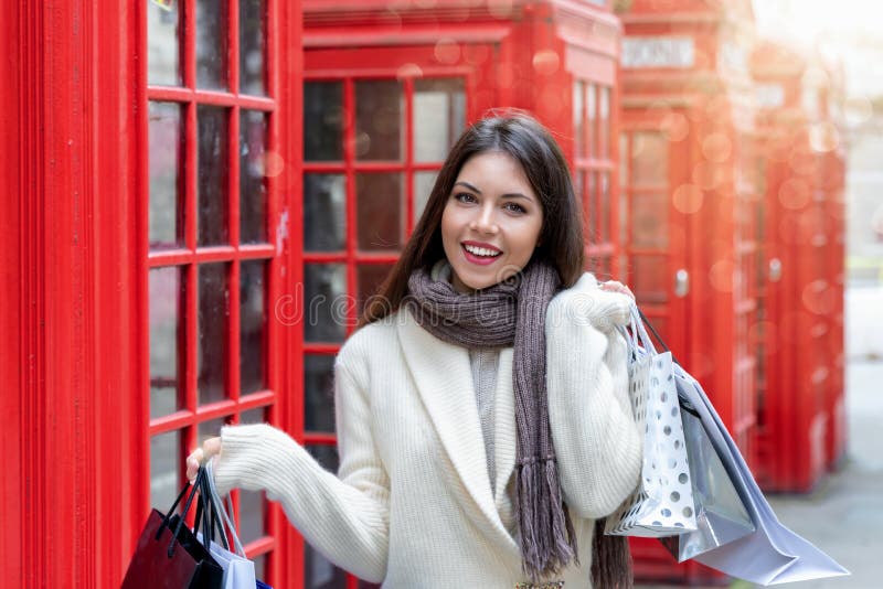 Vrouw met het winkelen zakken voor rode telefooncellen in Londen, het UK royalty-vrije stock fotografie Vrouw met het winkelen zakken voor rode telefooncellen in Londen, het UK royalty-vrije stock fotografie