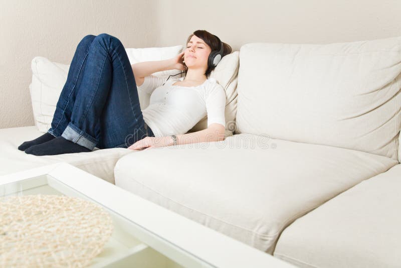 Young woman on a couch listening to music with headphones. Young woman on a couch listening to music with headphones