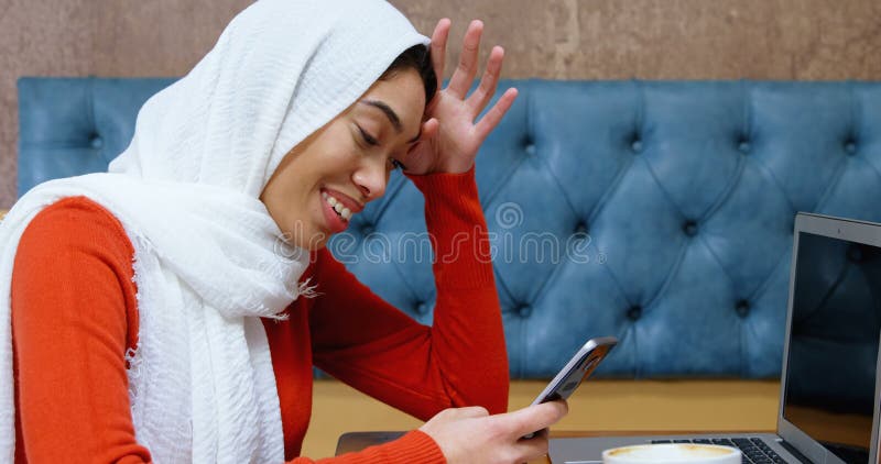 Vrouw met mobiele telefoon in cafetaria 4.000