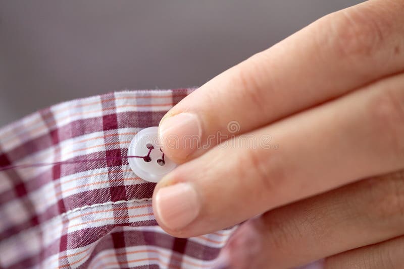 Vrouw met naald het stikken op knoop aan overhemd