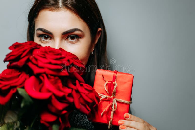Vrouw met rood giftdoos en boeket van mooie rozen op grijs, royalty-vrije stock foto's Vrouw met rood giftdoos en boeket van mooie rozen op grijs, royalty-vrije stock foto's