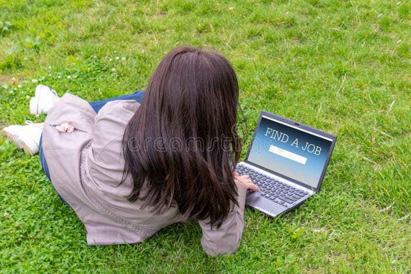 Woman mom on maternity leave sitting on the grass and using, working outdoor on laptop. Female with long hair typing on computer, hands on keyboard. Freelance work, job. Unrecognizable girl with notebook. inscription FIND A JOB. Woman mom on maternity leave sitting on the grass and using, working outdoor on laptop. Female with long hair typing on computer, hands on keyboard. Freelance work, job. Unrecognizable girl with notebook. inscription FIND A JOB.