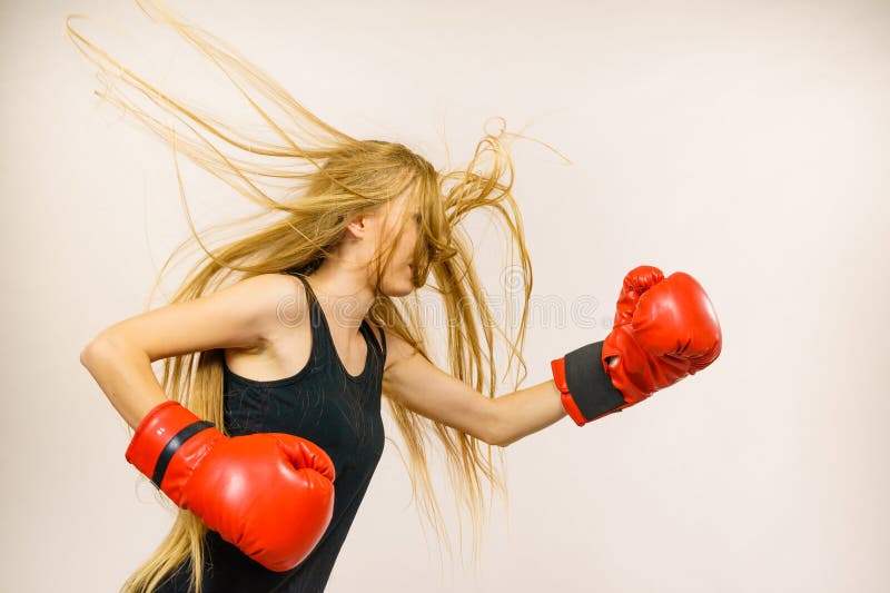 Blonde long hair woman in big red gloves boxing. Female fight for equal rights for women. Side view. Gender equality concept. Blonde long hair woman in big red gloves boxing. Female fight for equal rights for women. Side view. Gender equality concept