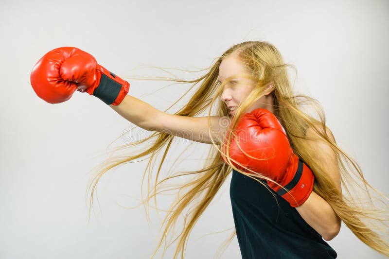 Blonde long hair woman in big red gloves boxing. Female fight for equal rights for women. Side view. Gender equality concept. Blonde long hair woman in big red gloves boxing. Female fight for equal rights for women. Side view. Gender equality concept