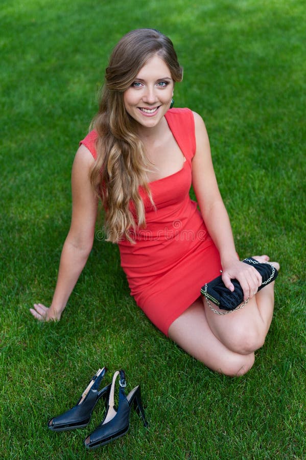 Vrouw in rode kledingszitting op groen gras stock fotografie Vrouw in rode kledingszitting op groen gras stock fotografie