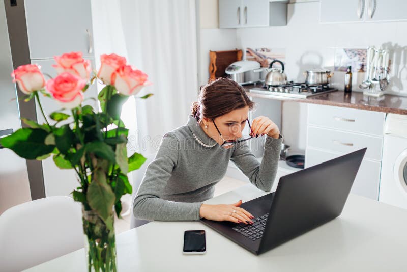 Vrouw spreken die aan laptop op moderne keuken werken Het boze geïrriteerde freelancer staren bij het scherm royalty-vrije stock foto Vrouw spreken die aan laptop op moderne keuken werken Het boze geïrriteerde freelancer staren bij het scherm royalty-vrije stock foto