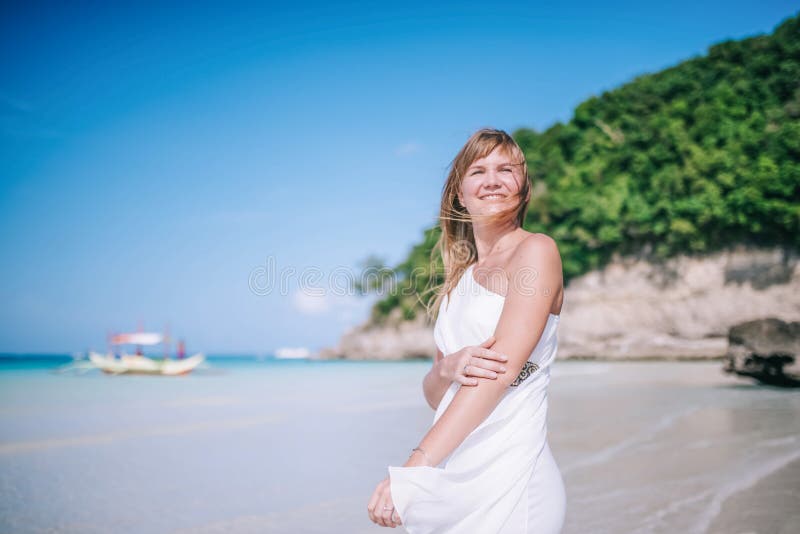 Portrait of the beautiful blond long hair woman dancing on the beach. Happy island lifestyle. White sand, blue cloudy sky and crystal sea of tropical beach. Vacation on the paradise island. Portrait of the beautiful blond long hair woman dancing on the beach. Happy island lifestyle. White sand, blue cloudy sky and crystal sea of tropical beach. Vacation on the paradise island.