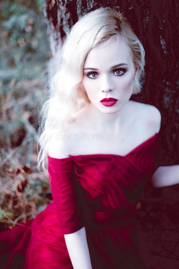 Vrouw van het manier de schitterende jonge blonde in mooie rode kleding in een sprookje bos magische atmosfeer Retoucheerd stemme stock fotografie Vrouw van het manier de schitterende jonge blonde in mooie rode kleding in een sprookje bos magische atmosfeer Retoucheerd stemme stock fotografie