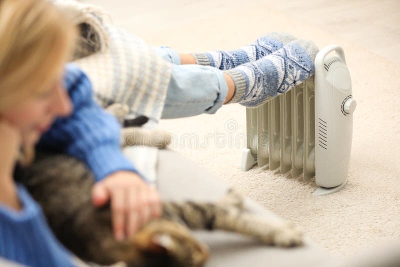 Vrouw warmt voetjes op elektrisch verwarmingstoestel thuis stock fotografie Vrouw warmt voetjes op elektrisch verwarmingstoestel thuis stock fotografie