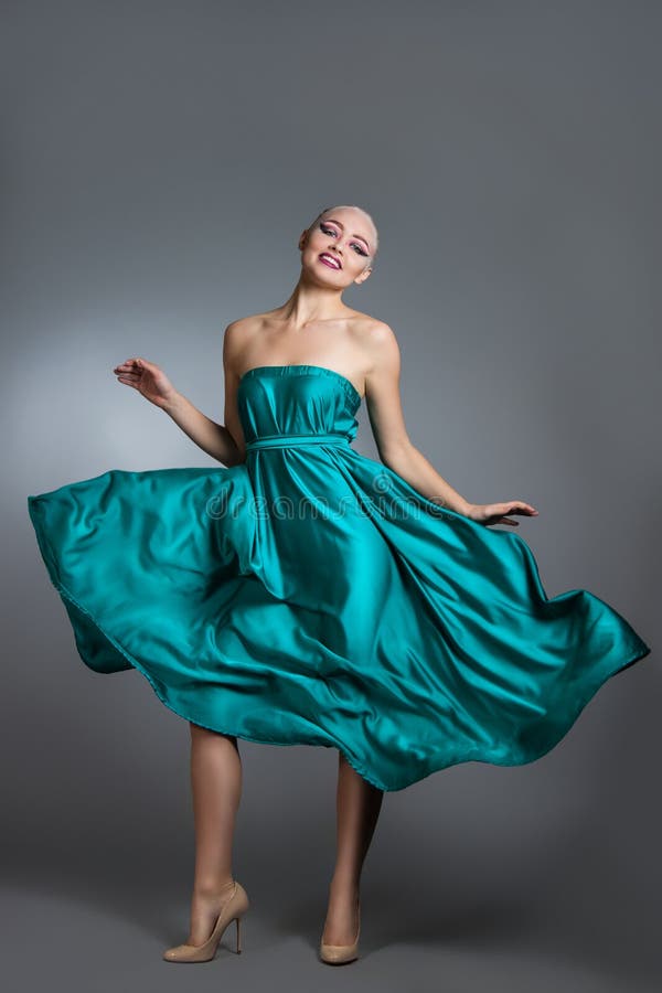 Vrouw in zijdekleding die op wind golven Vliegende en fladderende togadoek over grijze achtergrond royalty-vrije stock foto's Vrouw in zijdekleding die op wind golven Vliegende en fladderende togadoek over grijze achtergrond royalty-vrije stock foto's