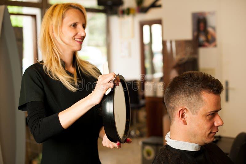 Vrouwelijk kapper scherp haar van glimlachende mensencliënt bij schoonheid stock fotografie Vrouwelijk kapper scherp haar van glimlachende mensencliënt bij schoonheid stock fotografie