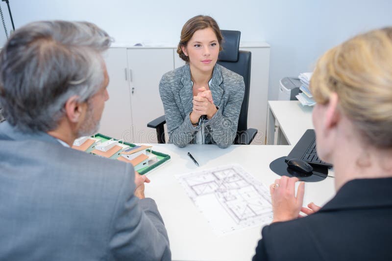 Vrouwelijke architect die aan paar in vergadering luisteren stock afbeelding Vrouwelijke architect die aan paar in vergadering luisteren stock afbeelding