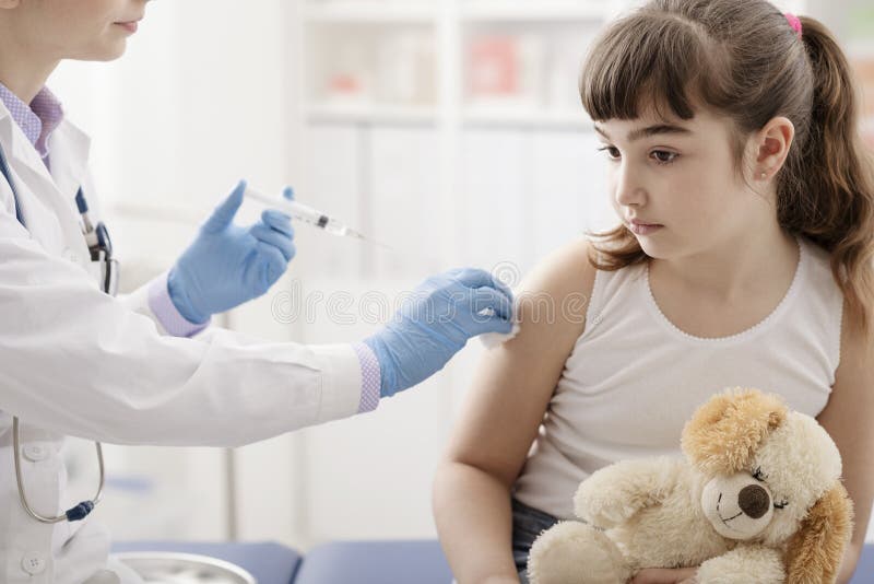 Vrouwelijke arts die een injectie geven aan een jong leuk meisje stock afbeeldingen Vrouwelijke arts die een injectie geven aan een jong leuk meisje stock afbeeldingen