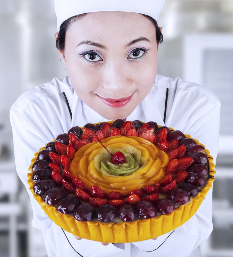 Vrouwelijke chef-kok die een vruchten cake houden stock foto Vrouwelijke chef-kok die een vruchten cake houden stock foto