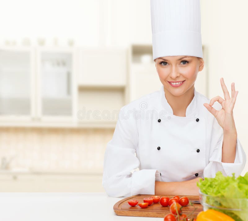 Vrouwelijke chef-kok met groenten die o.k. teken tonen stock foto Vrouwelijke chef-kok met groenten die o.k. teken tonen stock foto