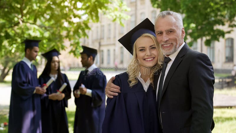 Vrouwelijke gediplomeerde koesterende papa en het glimlachen in camera, succesvolle toekomst, carrière stock afbeelding Vrouwelijke gediplomeerde koesterende papa en het glimlachen in camera, succesvolle toekomst, carrière stock afbeelding