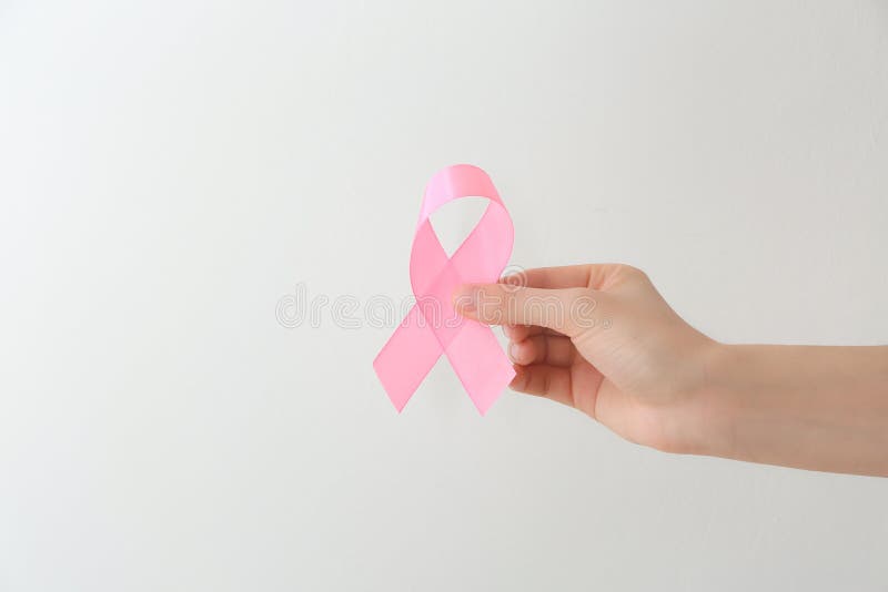 Vrouwelijke hand die roze lint op lichte achtergrond houden De voorlichtingsconcept van borstkanker stock fotografie Vrouwelijke hand die roze lint op lichte achtergrond houden De voorlichtingsconcept van borstkanker stock fotografie