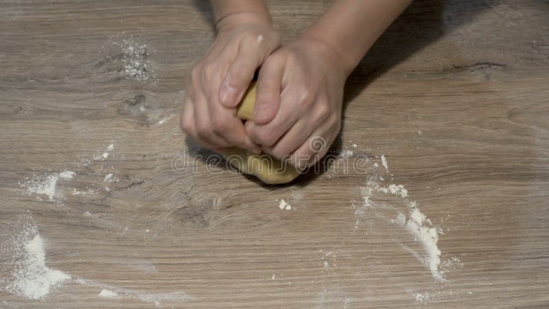 Vrouwelijke handen die een stuk geel deeg op een houten tafel knippen. het begrip koken. de weergave bovenaan