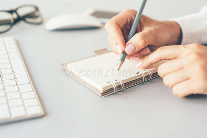 Vrouwelijke handen die in notitieboekje schrijven royalty-vrije stock fotografie Vrouwelijke handen die in notitieboekje schrijven royalty-vrije stock fotografie