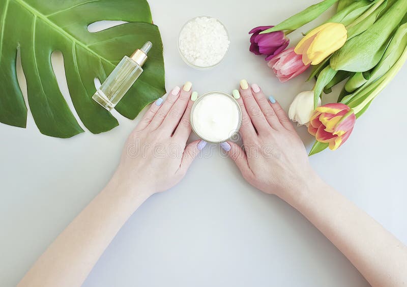 Vrouwelijke handenmanicure, van de de zomertherapie van de essentievochtinbrengende cr?me de room kosmetische tulp op een gekleur royalty-vrije stock foto Vrouwelijke handenmanicure, van de de zomertherapie van de essentievochtinbrengende cr?me de room kosmetische tulp op een gekleur royalty-vrije stock foto