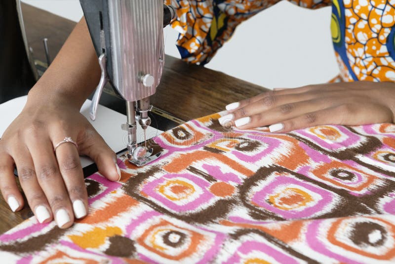 Vrouwelijke kleermaker die gevormde doek op naaimachine stikken