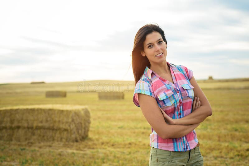 Confident female farmer looking confident portrait in countryside rural field at sunset. Country beautiful woman. Confident female farmer looking confident portrait in countryside rural field at sunset. Country beautiful woman.