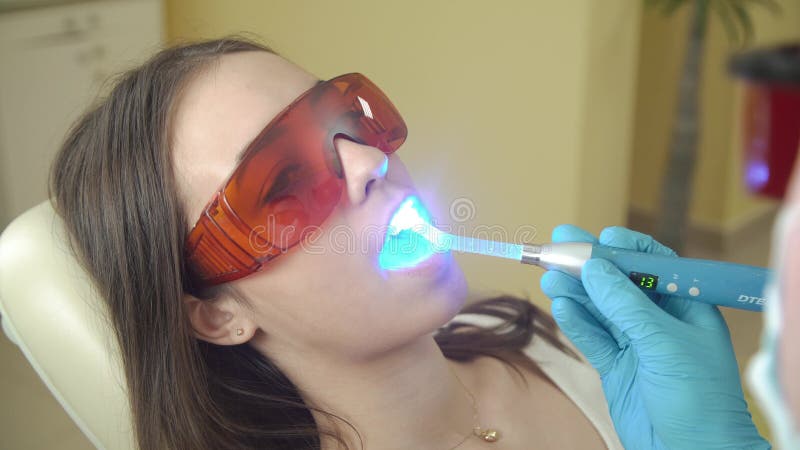 Vrouwelijke patiënt die behandeling met tand UVlichtmateriaal krijgen Tand bureau