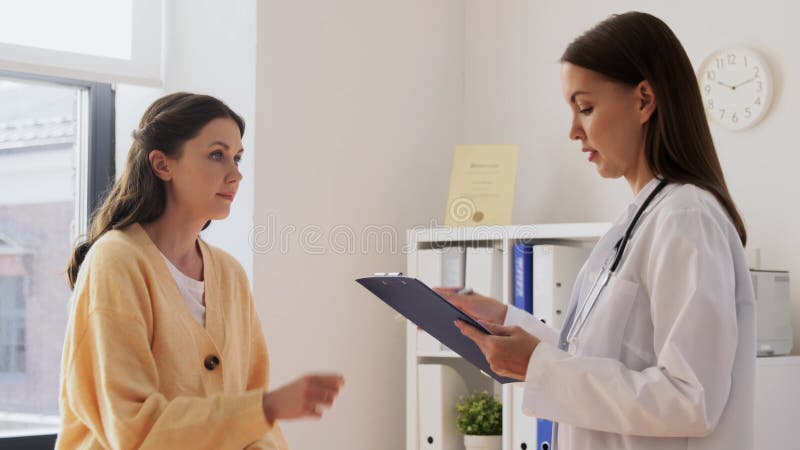 Vrouwelijke patiënt die papieren geeft aan arts in de kliniek