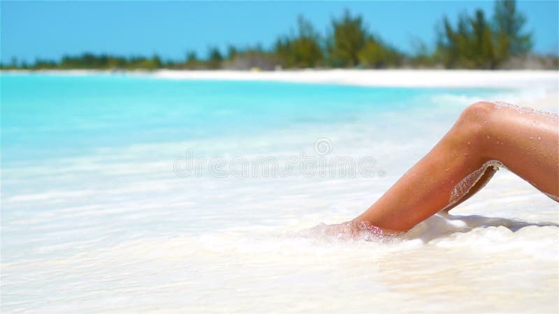 Vrouwelijke slanke gelooide benen op een wit tropisch strand Langzame video