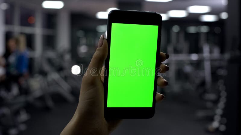 Vrouwelijke smartphone van de handholding in gymnastiek, het groene scherm, online geschiktheidstoepassing royalty-vrije stock foto's Vrouwelijke smartphone van de handholding in gymnastiek, het groene scherm, online geschiktheidstoepassing royalty-vrije stock foto's