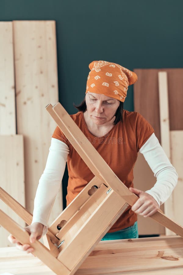 Vrouwelijke timmerman die houten stoelzetel in workshop herstellen royalty-vrije stock foto Vrouwelijke timmerman die houten stoelzetel in workshop herstellen royalty-vrije stock foto