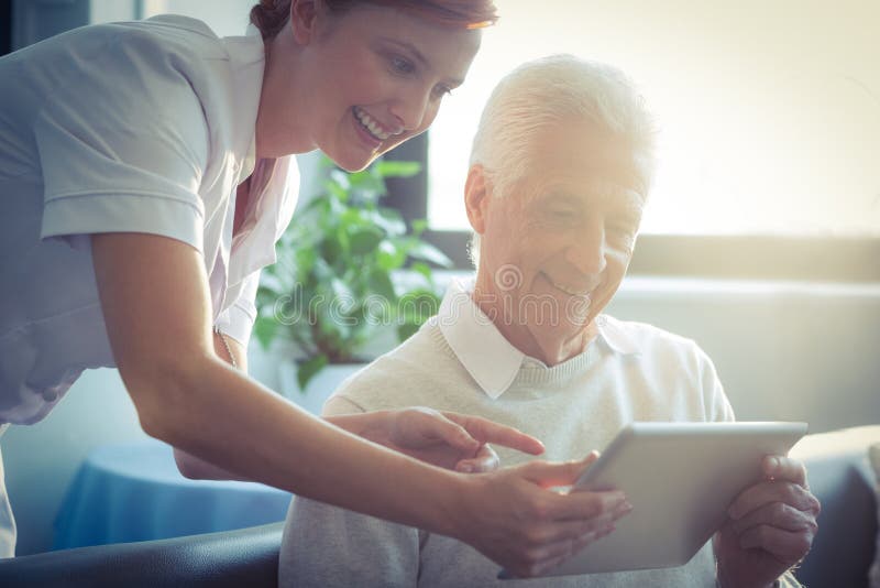 Vrouwelijke verpleegster die medisch rapport aan de hogere mens over digitale tablet tonen stock fotografie Vrouwelijke verpleegster die medisch rapport aan de hogere mens over digitale tablet tonen stock fotografie