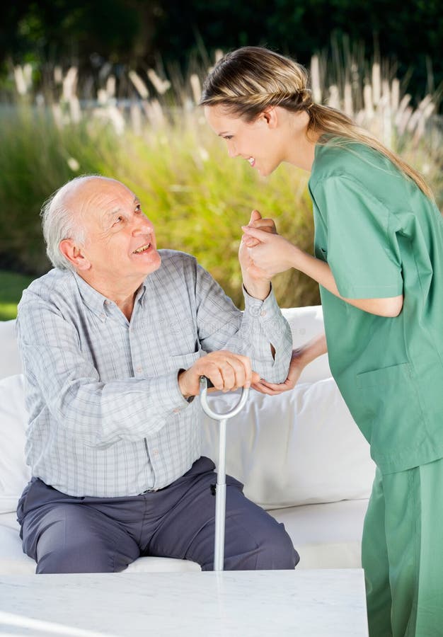 Vrouwelijke Verpleegster Helping Senior Man omhoog Te worden van stock afbeelding Vrouwelijke Verpleegster Helping Senior Man omhoog Te worden van stock afbeelding