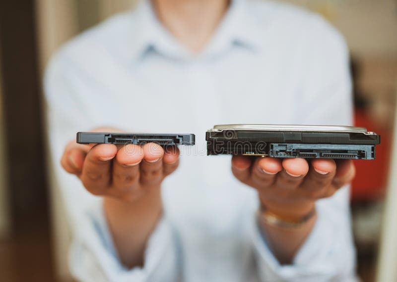 IT woman holding presenting two different  generations of computer disks HDD hard disk drive and SSD solid state drive - offering them to viewer. IT woman holding presenting two different  generations of computer disks HDD hard disk drive and SSD solid state drive - offering them to viewer