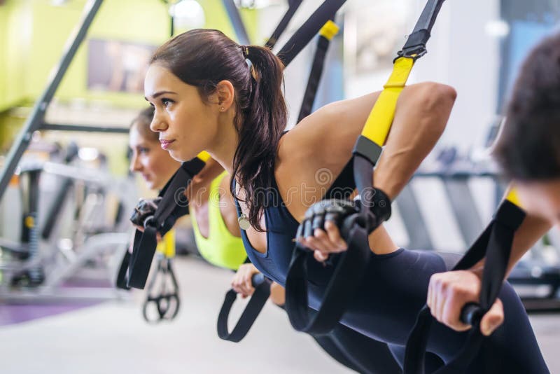 Vrouwen die duw UPS opleidingswapens met trx doen royalty-vrije stock afbeeldingen Vrouwen die duw UPS opleidingswapens met trx doen royalty-vrije stock afbeeldingen