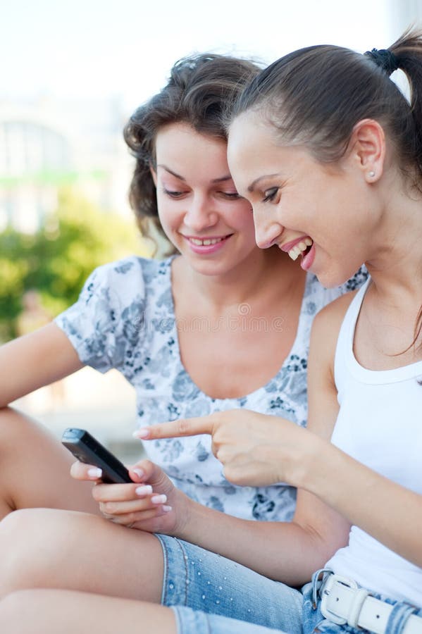 Vrouwen die en cellphone lachen bekijken royalty-vrije stock foto's Vrouwen die en cellphone lachen bekijken royalty-vrije stock foto's